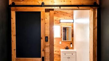 A wooden interior with a sliding door, a white cabinet, and a mirror.