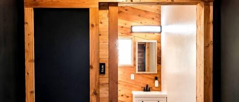 Un intérieur en bois avec une porte coulissante, un meuble blanc et un miroir.