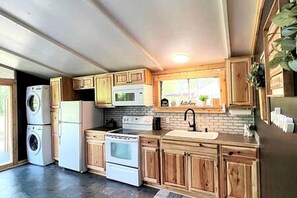 A kitchen with wooden cabinets, a stove, a microwave, a sink, and a window.