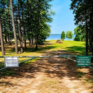 Una entrada tancada amb reixa a l'àrea recreativa de Crystal Cove Copeland Creek, amb una vista clara d'un llac i arbres.