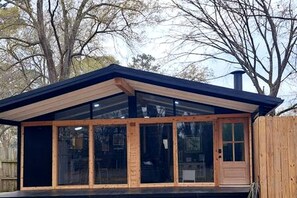 Ein modernes Gebäude mit einer großen Glastür, einer Holzfassade und einer überdachten Terrasse.