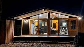 A modern house with a glass front, wooden exterior, and a deck area. - Fish Cabin at the Pines: Cozy Cabin near Lake O' the Pines in Jefferson, Texas (Jefferson)