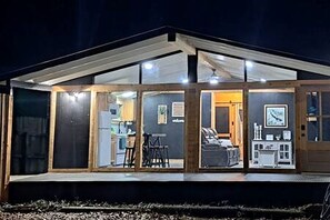 Ein modernes Haus mit Glasfront, Holzinnenarchitektur und einer durch die Scheibe einsehbarer Küche.