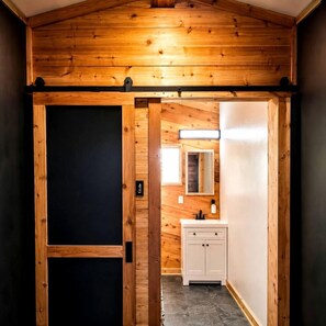 Un interior de fusta amb una porta corredissa, un armari blanc i un mirall.