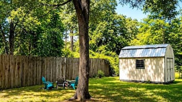 A fenced yard with a tree, a small shed, and a table with chairs.