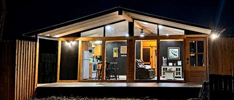 A modern house with a glass front, wooden exterior, and a deck area.