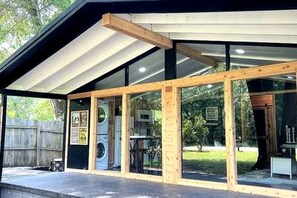 Un bâtiment moderne doté d’un espace extérieur couvert, de grandes fenêtres et d’équipements de buanderie visibles.