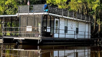 A houseboat with a covered deck, windows, and a flag.