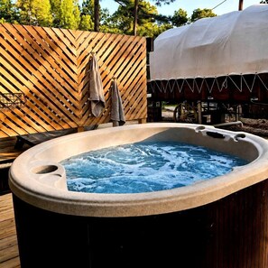 Un jacuzzi con terraza de madera y una zona cubierta al fondo.