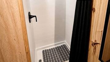 A shower area with a showerhead, a towel rack, and a shower mat.