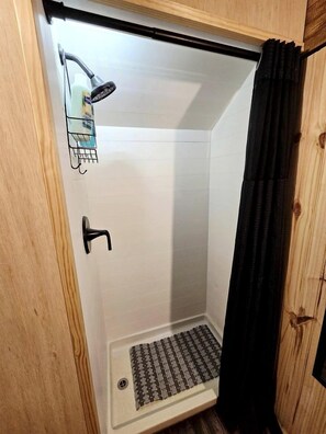 Un espacio de ducha con ducha, dispensador de jabón y desagüe.