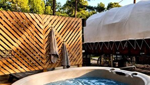 Un bain à remous avec une terrasse en bois et un espace couvert en arrière-plan.