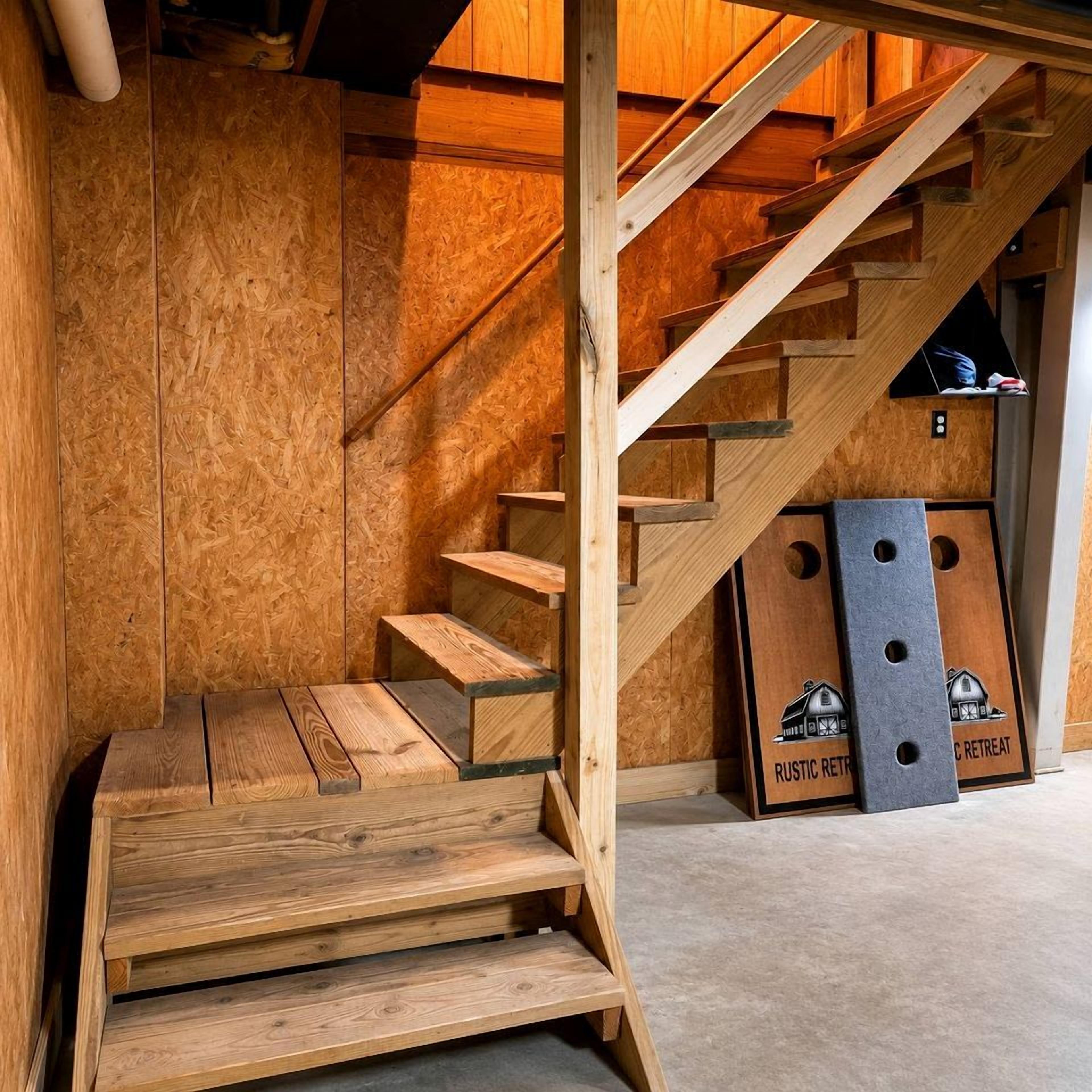 A wooden staircase leading to a loft area with a loft bed and a small table.