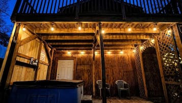 Una terraza de madera con un jacuzzi, un área de estar cubierta y una puerta.