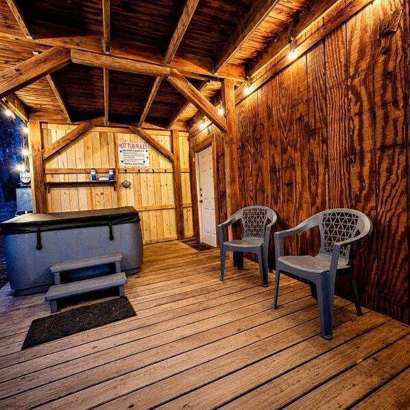 A wooden interior with a hot tub, two chairs, and a bench.