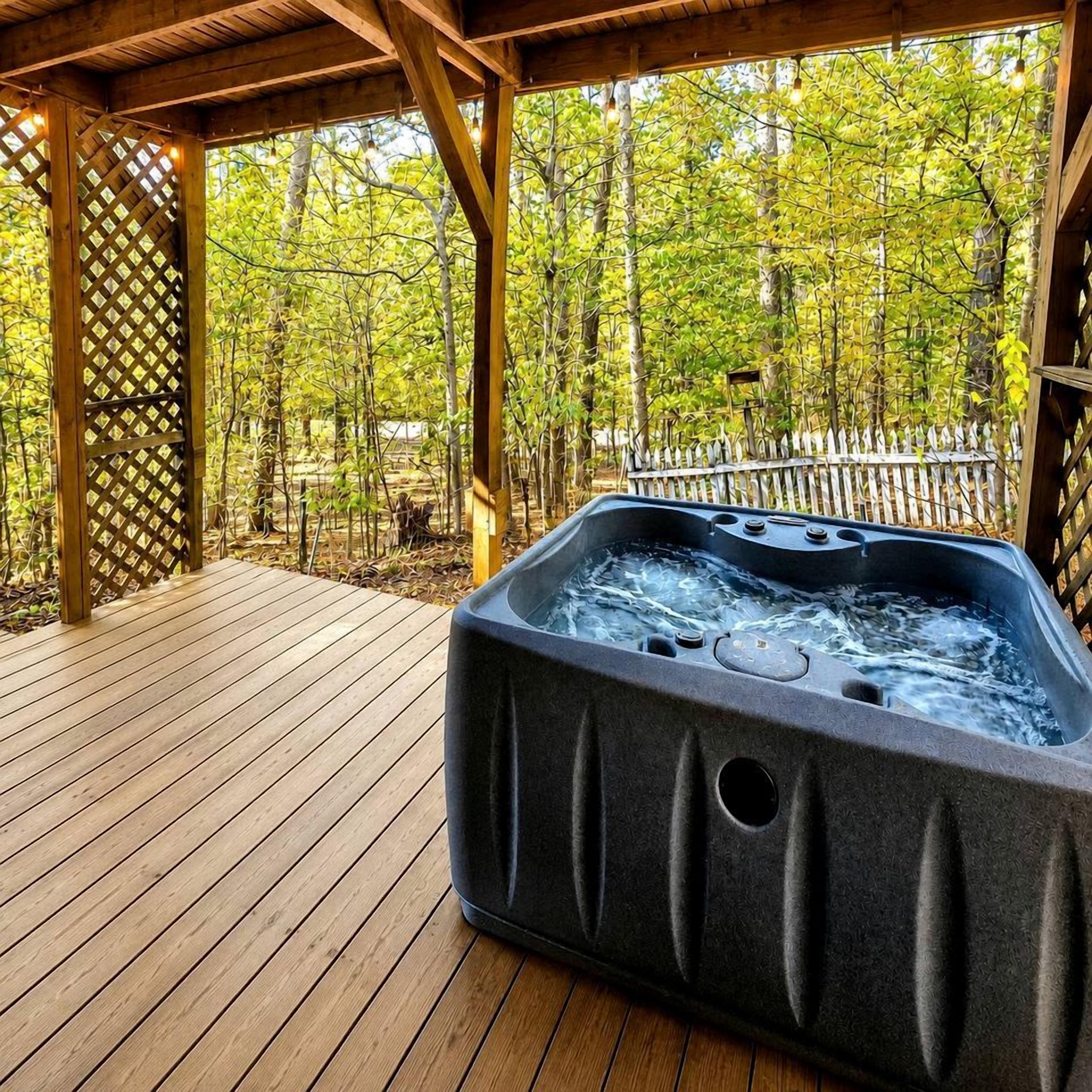A hot tub on a wooden deck with a wooden pergola overhead, surrounded by trees.