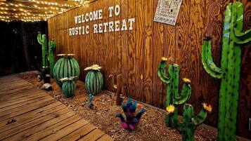 Eine Holzwand mit einem Schild, das 'WELCOME TO Rustic Retreat' zeigt, und dekorativen Kakteen.