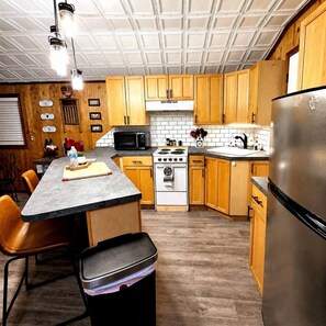Una cocina con armarios de madera, estufa, microondas y refrigerador.