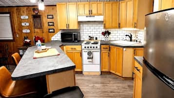 A kitchen with wooden cabinets, a stove, a microwave, and a refrigerator.