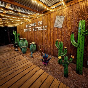 A wooden wall with a sign reading 'WELCOME TO Rustic Retreat' and decorative cacti.
