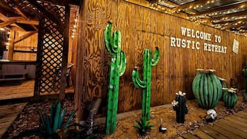 A rustic retreat entrance with wooden walls, a welcome sign, and decorative cacti.