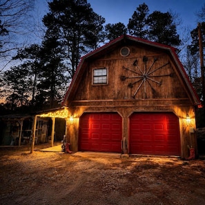 A wooden barn with two red garage doors, a window, and a star-shaped decoration on the wall. - Rustic Retreat near Lake O the Pines: Gorgeous Barn in Warlock, Texas (Warlock)