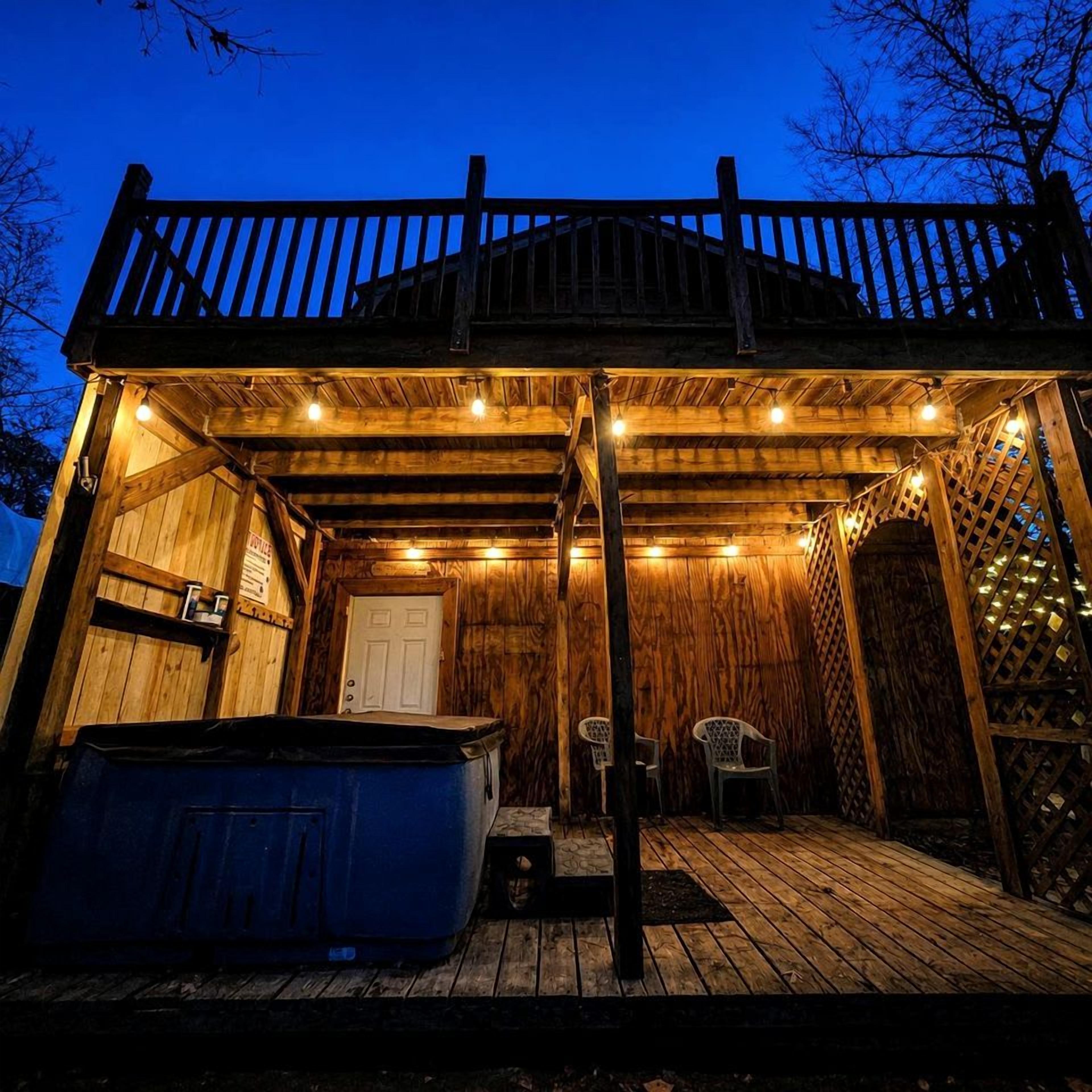 A wooden deck with a hot tub, a covered seating area, and a door.