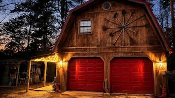 Un granero de madera con dos puertas de garaje rojas, una ventana y una decoración en forma de estrella en la pared.