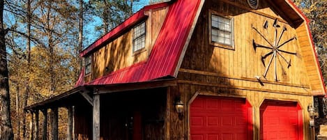 Ein rustikales Scheunenhaus mit rotem Dach, Holzverkleidung und einer Garage mit roten Türen.