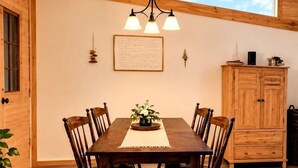 A dining area with a wooden table and chairs, a chandelier, and a view of the sky through a skylight.