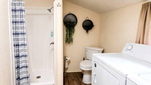 Een kleine badkamer met douche, toilet en een wasmachine.