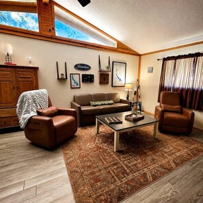 A cozy living room with a brown leather sofa, a coffee table, and a patterned rug. - The Knotty Pine on Lake O the Pines: Waterfront Vacation Rental in Jefferson, Texas (Jefferson)