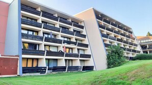 Een hotel met meerdere verdiepingen, balkons, een plat dak en een gazon ervoor.