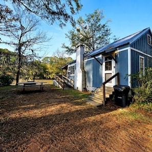 Un edificio rústico con terraza de madera, escaleras y mesa de picnic.