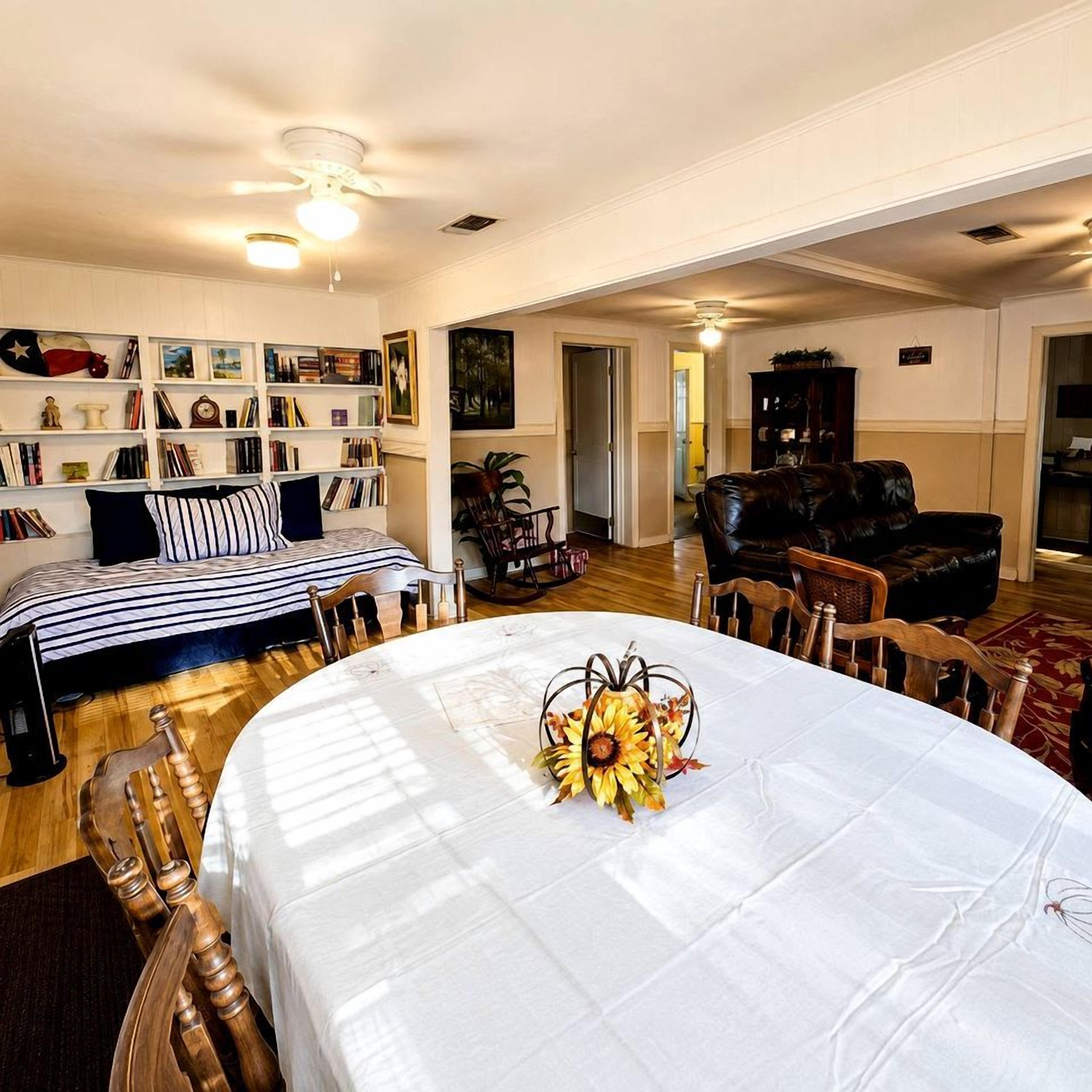 Quarto com mesa de jantar posta para quatro pessoas, um sofá, estante e lareira.