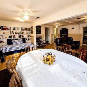 A room with a dining table set for four, a sofa, a bookshelf, and a fireplace.