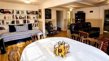 Una habitación con una mesa de comedor lista para cuatro personas, un sofá, una estantería y una chimenea.