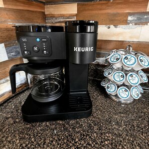 En Keurig kaffemaskine med en krystalglas kande og vandbeholder på en granitbordplade.