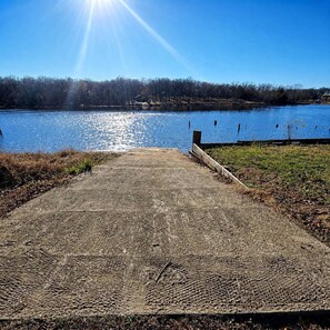 Un muelle de concreto que se adentra en un lago tranquilo con un cielo despejado.