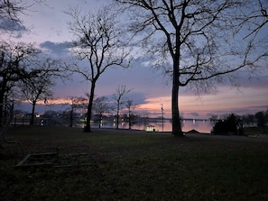 A park with trees, a bench, and a body of water in the background.