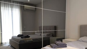 A modern bedroom with a large mirror, a sofa, a bed, and a nightstand.