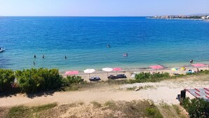 A beach with clear blue water, umbrellas, and lounge chairs. - Beachfront penthouse Pearl (Povljana)