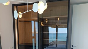 A modern bedroom with a bed, a wardrobe, and a view of the sea. - Beachfront penthouse Pearl (Povljana)
