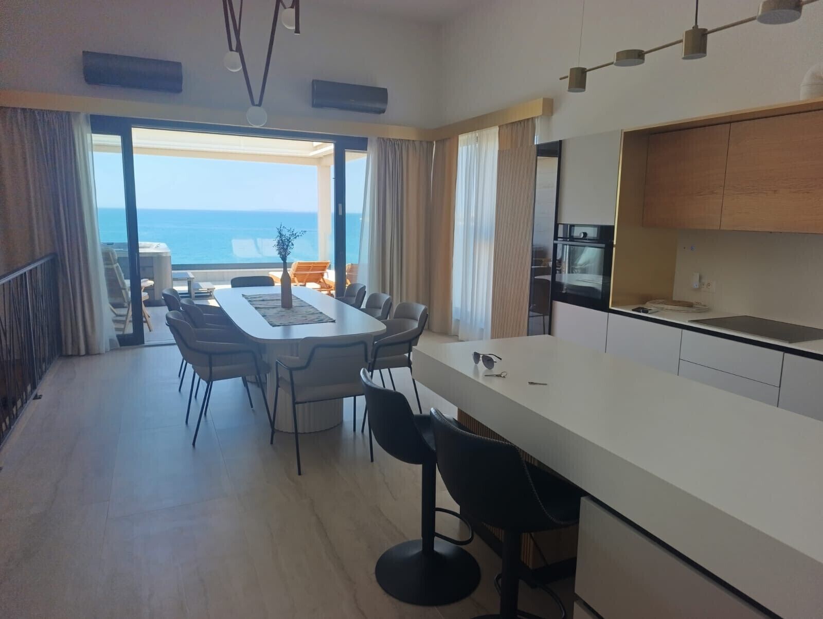 Una cocina moderna con una isla grande, comedor con sillas y vistas al mar.