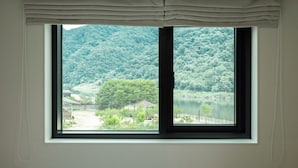 Una ventana con vista a un lago y colinas boscosas.