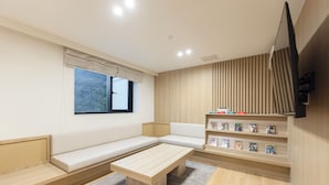 Una sala de estar moderna con un sofá, una mesa de centro, una estantería y un ventanal con vistas a árboles.