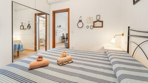 A bedroom with a bed, a mirror, a bedside table, and a wall-mounted lamp. - Casa Susanna – Your Retreat in Calasetta: Sea, Culture, and Relaxation (Calasetta)