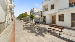 A quiet street with buildings, a bench, and a café with outdoor seating. - Casa Susanna – Your Retreat in Calasetta: Sea, Culture, and Relaxation (Calasetta)