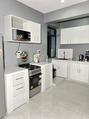 Una cucina moderna con mobili bianchi, forno integrato, microonde e piano cottura a gas.