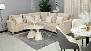 Ein modernes Wohnzimmer mit einem beigefarbenen Ecksofa, zwei runden Couchtischen und einem Esstisch mit Stühlen.